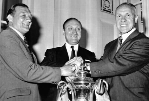 G67ADK Hands across the FA Cup as new Liverpool manager Bobby Paisley (left) receives the good wishes of club chairman John Smith (centre) and retiring manager Bill Shankly after his appointment had been announced at the club's AGM. Paisley, a former Liverpool wing-half, has been Shankley's assistant for three years. July 1974. (PA Images / Alamy Stock Photo)